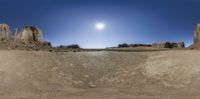 360 - turn view of the desert area with a large rock formation in front of a bright sunlit sky