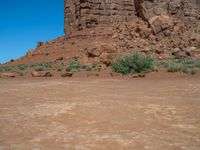 the rocks are brown and brown in color with green shrubs around them and a large, rocky mountain in the background