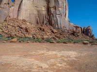 the rocks are brown and brown in color with green shrubs around them and a large, rocky mountain in the background