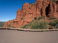 a person riding a bike in front of a mountain with cliffs and red rocks behind