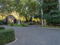 a driveway lined with trees and stone tiles in front of a church that has two spires