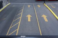 arrow symbols painted on a roadway with a light pole in the distance and a street lined by yellow curbing