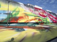 a large multi - colored building on the side of the street, with an artistic mural