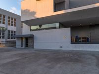 this building is a home with concrete exterior and some glass windows and doors on the third story