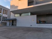 this building is a home with concrete exterior and some glass windows and doors on the third story