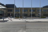 a building sitting next to an empty street in front of flags flying from poles and poles