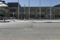 a building sitting next to an empty street in front of flags flying from poles and poles