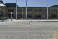 a building sitting next to an empty street in front of flags flying from poles and poles