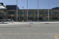 a building sitting next to an empty street in front of flags flying from poles and poles