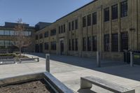 benches sit near a park in front of an old building with a building on either side