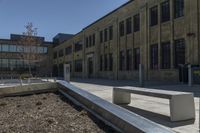 benches sit near a park in front of an old building with a building on either side