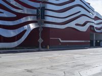 a fire hydrant sitting outside of an art gallery under a large red and white striped building