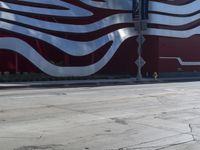 a fire hydrant sitting outside of an art gallery under a large red and white striped building