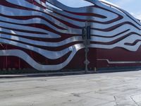 a fire hydrant sitting outside of an art gallery under a large red and white striped building