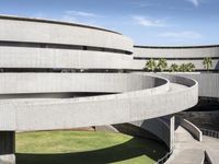 an art museum with lots of concrete and a large circular building with arches over the grass