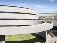 an art museum with lots of concrete and a large circular building with arches over the grass