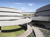 an art museum with lots of concrete and a large circular building with arches over the grass