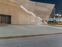 stairs are made out of concrete and beside two buildings at night time with lights on them