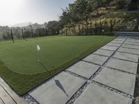 a artificial putting green in a tennis court with grass and flags on the edge of the green