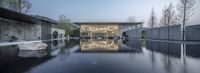 an artistic modern water feature sits at the base of a concrete structure in an otherwise peaceful setting