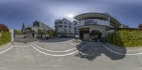 a 360 - camera lens view of an outside hotel lobby on a sunny day with trees and bushes on the curb