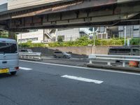 a city bus and car traveling down the road as it passes underneath an overpass