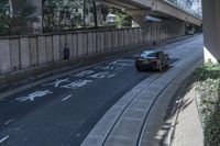 there is a large street under an overpass with graffiti on it and some bushes in the foreground