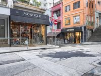 man riding on bike on a city street with buildings and a street sign saying monoclee