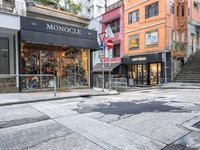 man riding on bike on a city street with buildings and a street sign saying monoclee