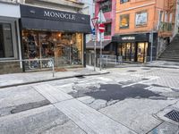 man riding on bike on a city street with buildings and a street sign saying monoclee