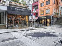 man riding on bike on a city street with buildings and a street sign saying monoclee