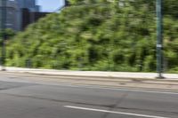 an asian boy riding a skateboard on a street near some bushes and grass that are in the background