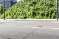 an asian boy riding a skateboard on a street near some bushes and grass that are in the background