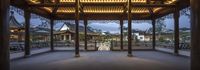 a view of the inside of an asian building with pillars and a walkway at dusk