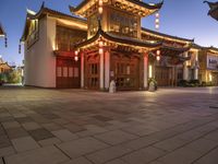 the light is on outside of the asian building at night in the city street, the lanterns are decorated with chinese style lights