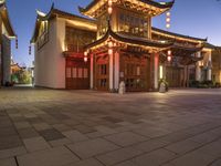 the light is on outside of the asian building at night in the city street, the lanterns are decorated with chinese style lights