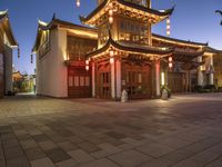 the light is on outside of the asian building at night in the city street, the lanterns are decorated with chinese style lights