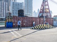 a man and a girl walking near container ships in an asian city area with tall buildings in the background