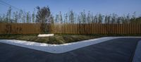 a large grass patch on a concrete patio near a wooden fence and a green lawn