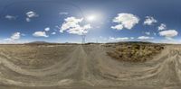 a view through the spherical lens of a dirt road with a telephone pole and sky