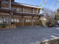 an asian style building with stone driveway next to it with a man walking past the door