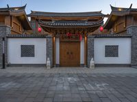 the asian style building has multiple doors and stone flooring, two red lanterns and lights