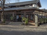 an asian style restaurant in an outside city area with a stone flooring and tall wooden columns