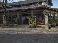 an asian style restaurant in an outside city area with a stone flooring and tall wooden columns