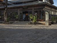 an asian style restaurant in an outside city area with a stone flooring and tall wooden columns