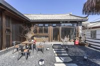 the patio has black furniture and white chairs around it, with a bamboo umbrella over one side and an orange chair next to a table in front