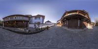 a wide angle shot of some old houses in an asian village on a cobble stone road