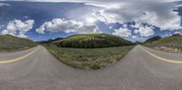 a very wide shot of the road going through some green hills of grass and bushes