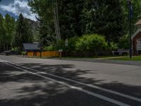 an empty street lined with trees and a mountain range in the distance in the back