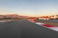 a photo of a dirt race track with sun setting in the distance of the track